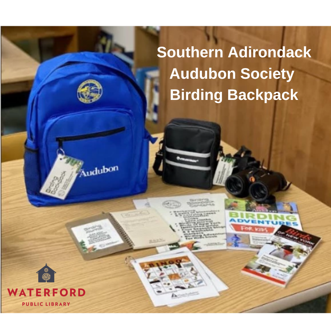 A blue backpack on a table with birding resources including binoculars.