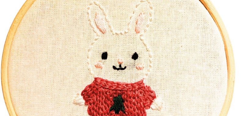 photo of an embroidery hoop featuring an embroidered bunny with a red sweater and the words "stay cozy" written underneath.