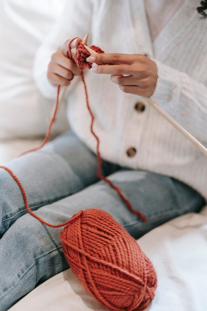 picture of a woman knitting with orange yarn